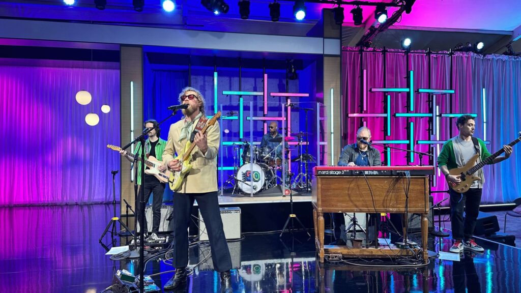 A live band performing on stage with colorful lighting and modern decor during Microsoft's 50th anniversary celebration.